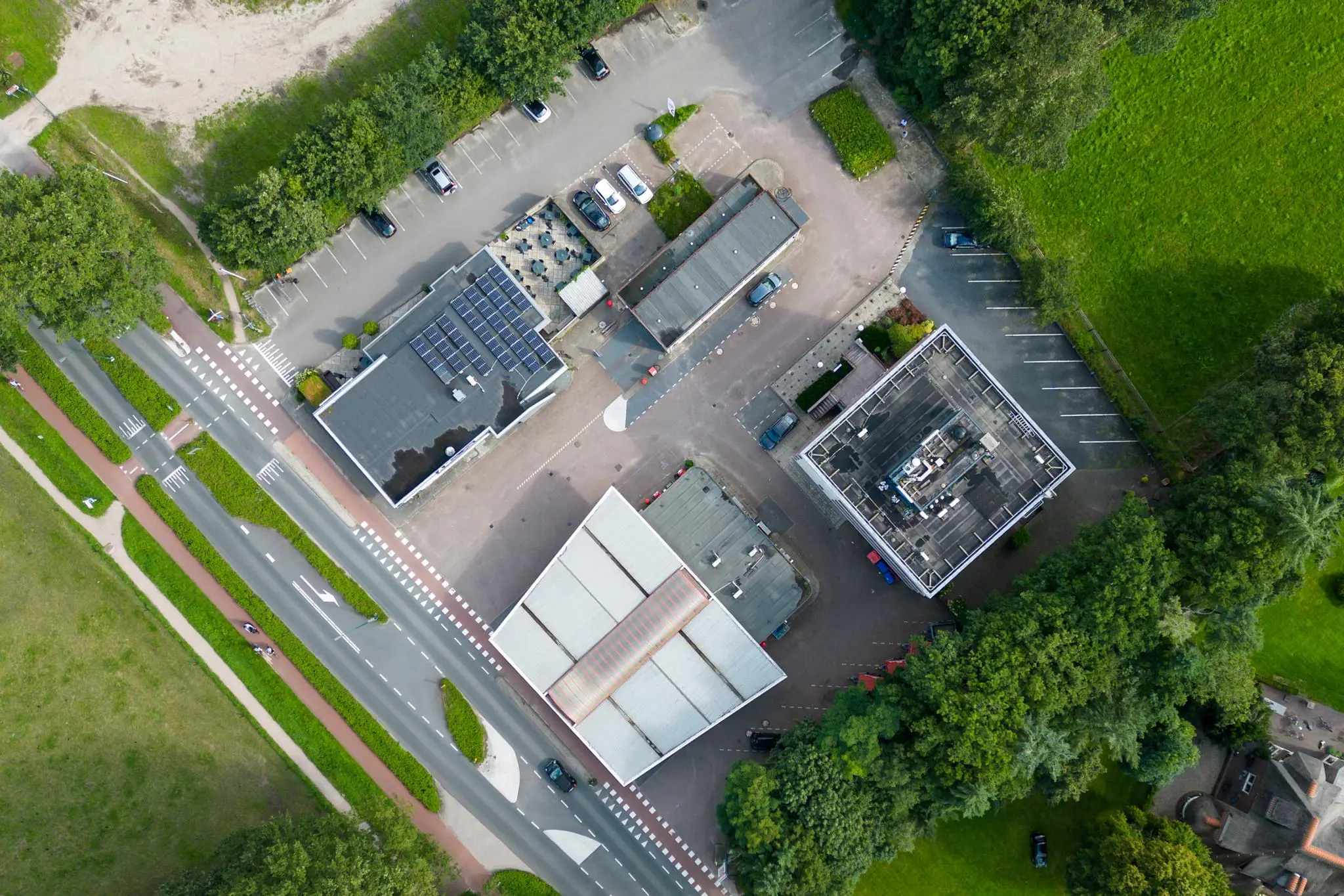 Luchtfoto van gebouwen en parkeerplaatsen aan de Birkstraat, omringd door groen en wegen.