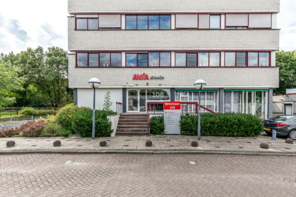Vooraanzicht van het kantoorgebouw AVIA Staete aan de Birkstraat 108, met een entree, naambord en omliggend groen.