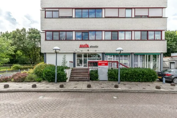 Vooraanzicht van het kantoorgebouw AVIA Staete aan de Birkstraat 108, met een entree, naambord en omliggend groen.