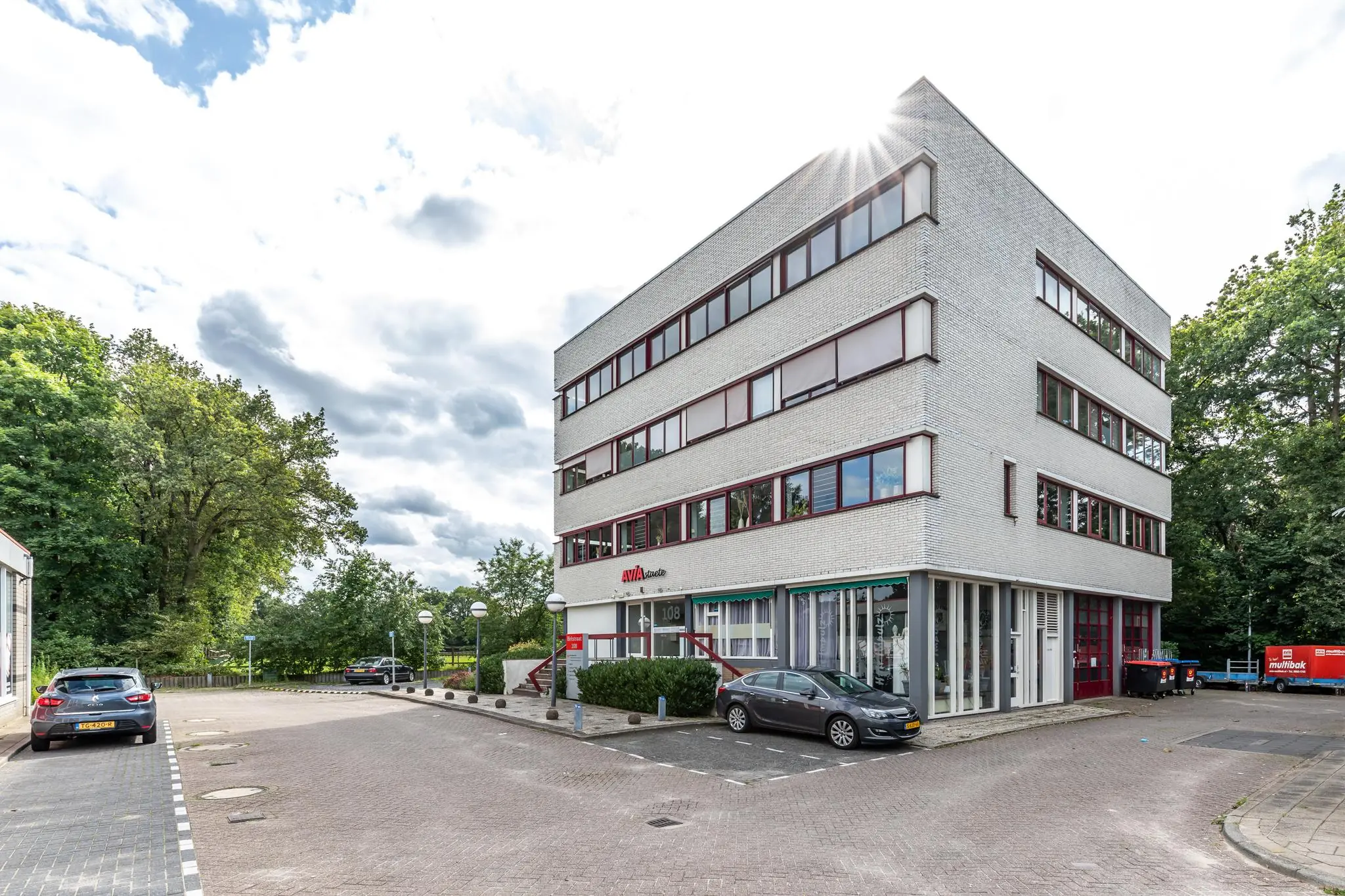 Wit kantoorgebouw aan de Birkstraat met rode raamkozijnen en geparkeerde auto's op de voorgrond.