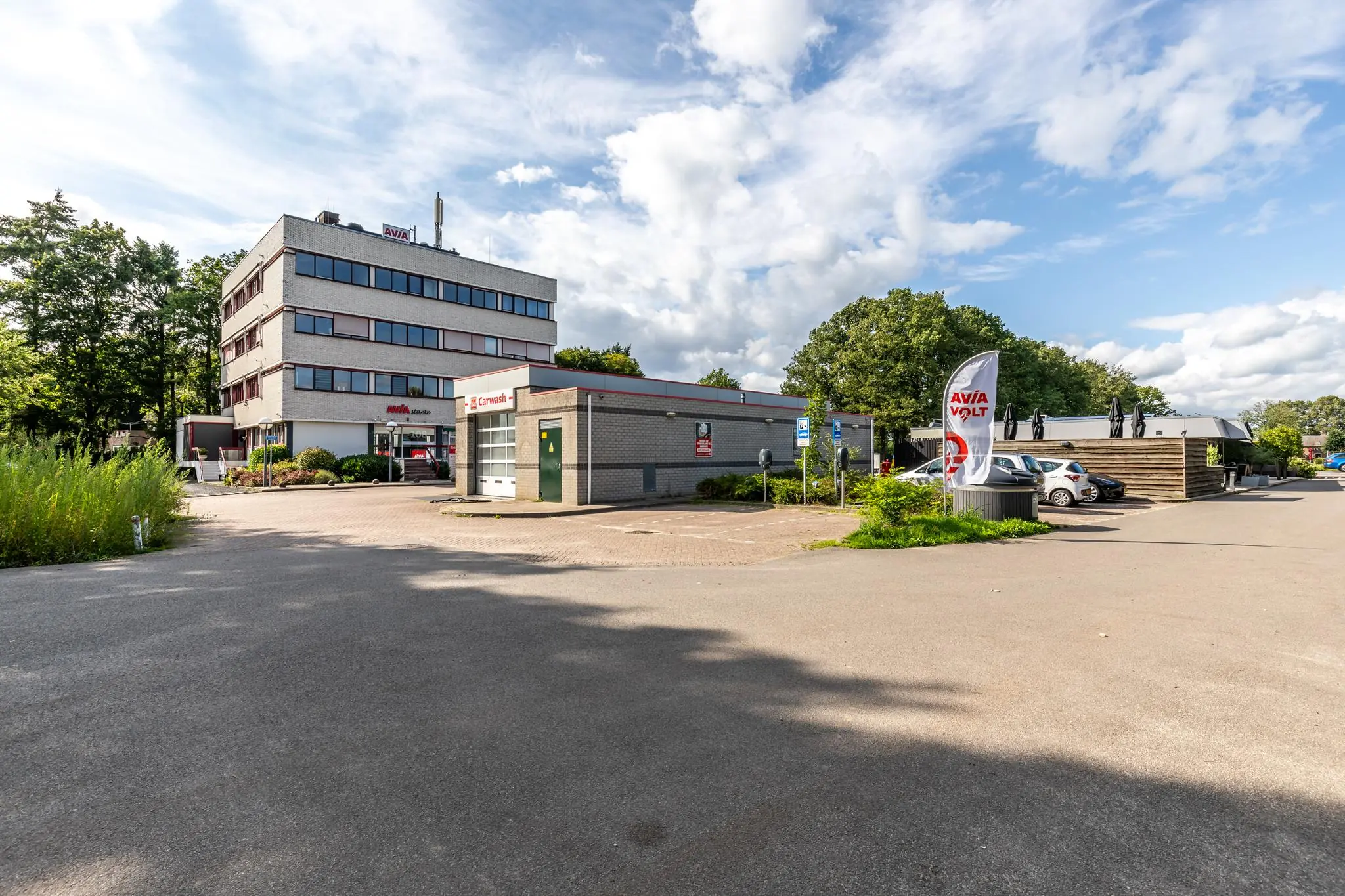 Tankstation AVIA Volt met carwash en kantoorgebouw aan de Birkstraat op een zonnige dag.