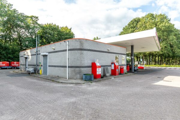 Buitenzicht op een AVIA tankstation aan de Birkstraat met grijs gebouw, rode brievenbus en parkeerapparaat.