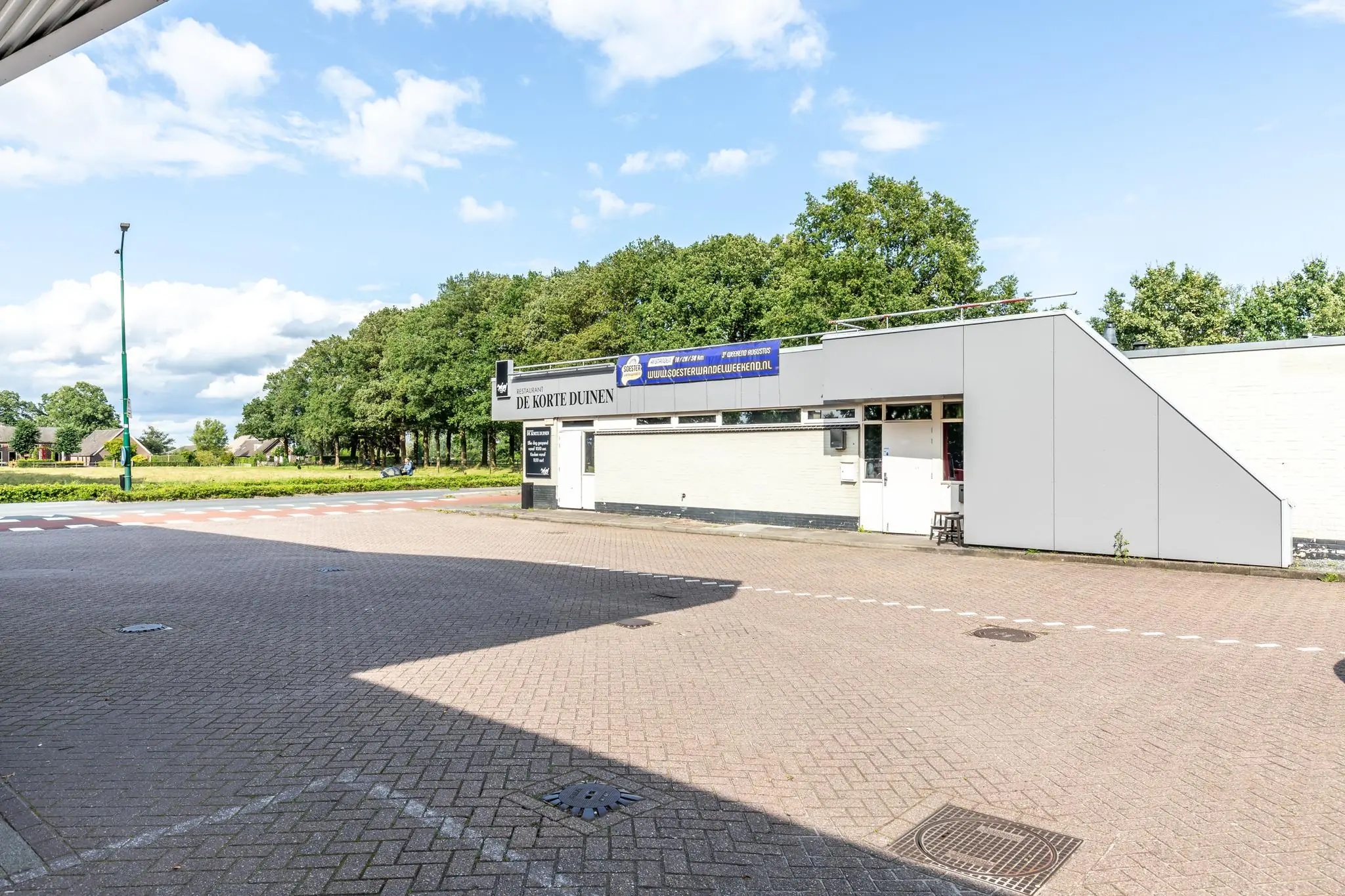 Voorzijde van restaurant De Korte Duinen aan de Birkstraat met zicht op een rustige straat en groene omgeving.