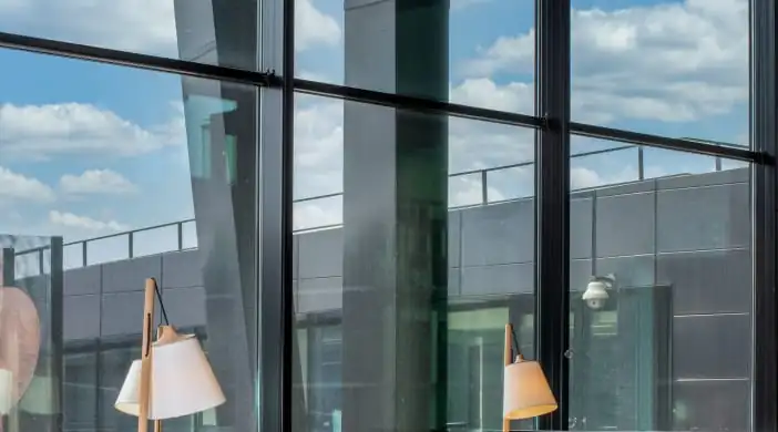 Grote ramen van een moderne kantoorruimte aan het Jonkerbosplein 52 in Nijmegen met uitzicht op een dakterras en blauwe lucht.