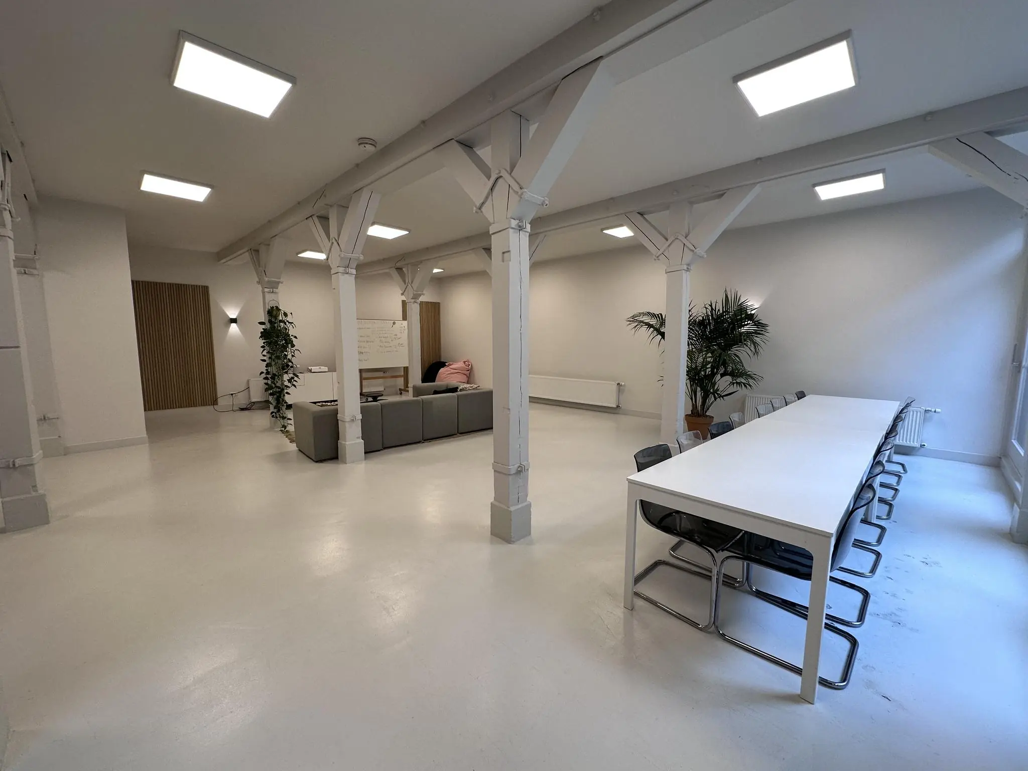 Ruime, modern ingerichte kantoorruimte aan de Bloemgracht met vergadertafel, zitgedeelte en witte houten steunpilaren.