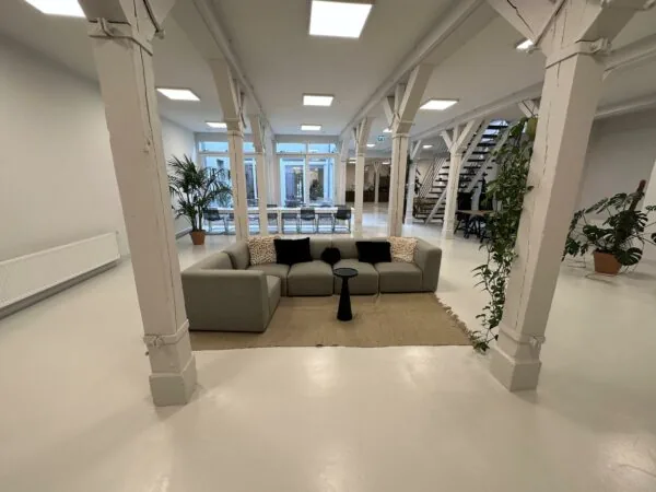 Moderne, open kantoorruimte aan de Bloemgracht met een grijze hoekbank, witte pilaren en veel groen.