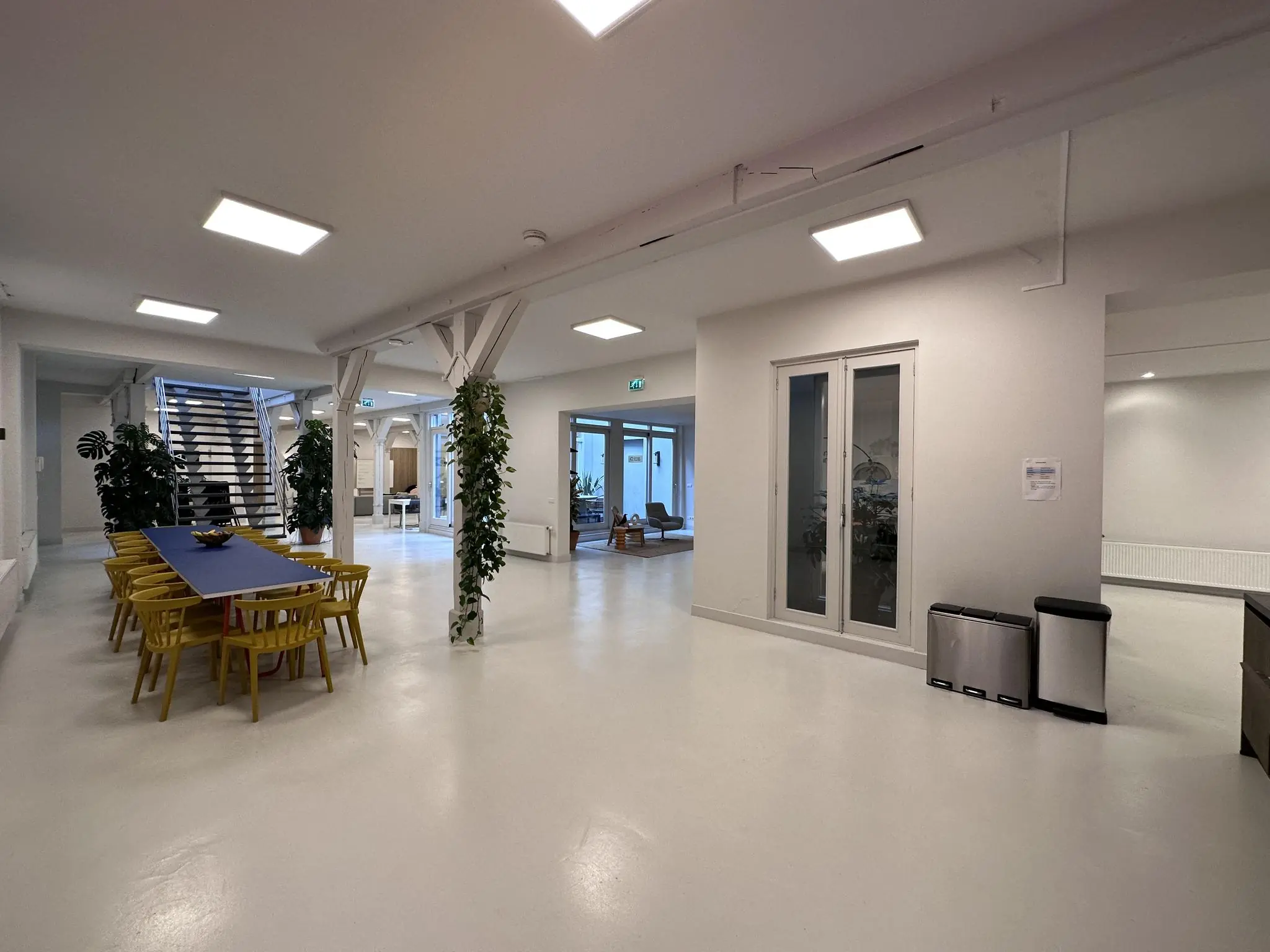 Moderne, open kantoorruimte aan de Bloemgracht met een lange vergadertafel, gele stoelen en een metalen trap naar boven.