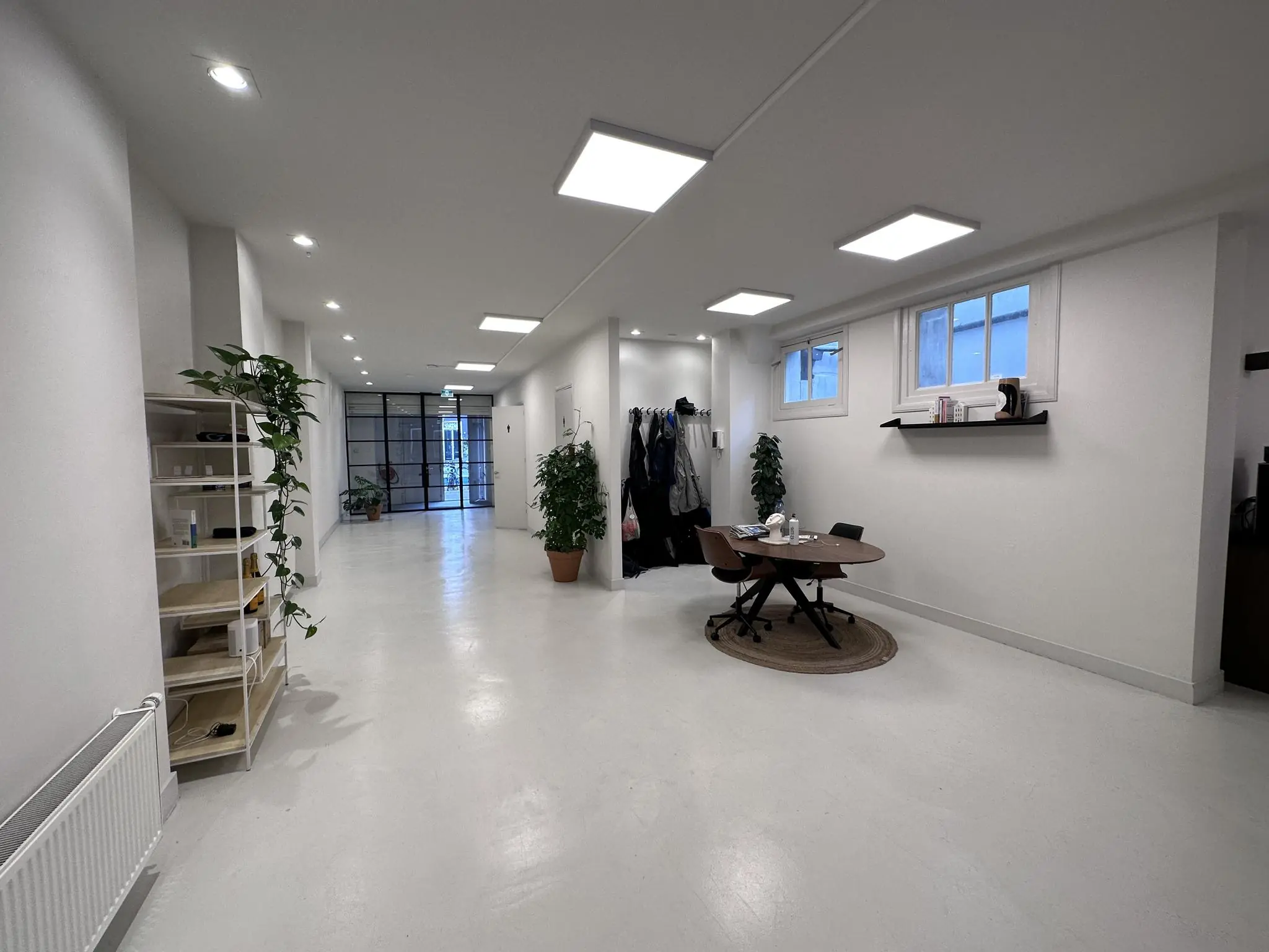 Moderne, minimalistisch ingerichte kantoorruimte aan de Bloemgracht met witte muren, planten, een ronde tafel en glazen deuren.