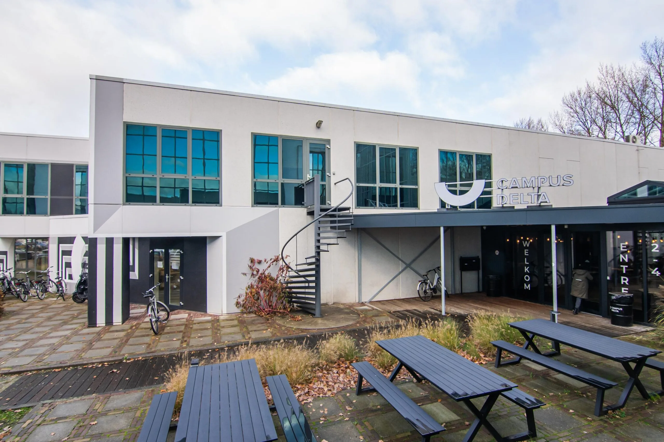 Modern office building of Campus Delta with blue picnic tables and spiral staircase at Rietbaan 24.