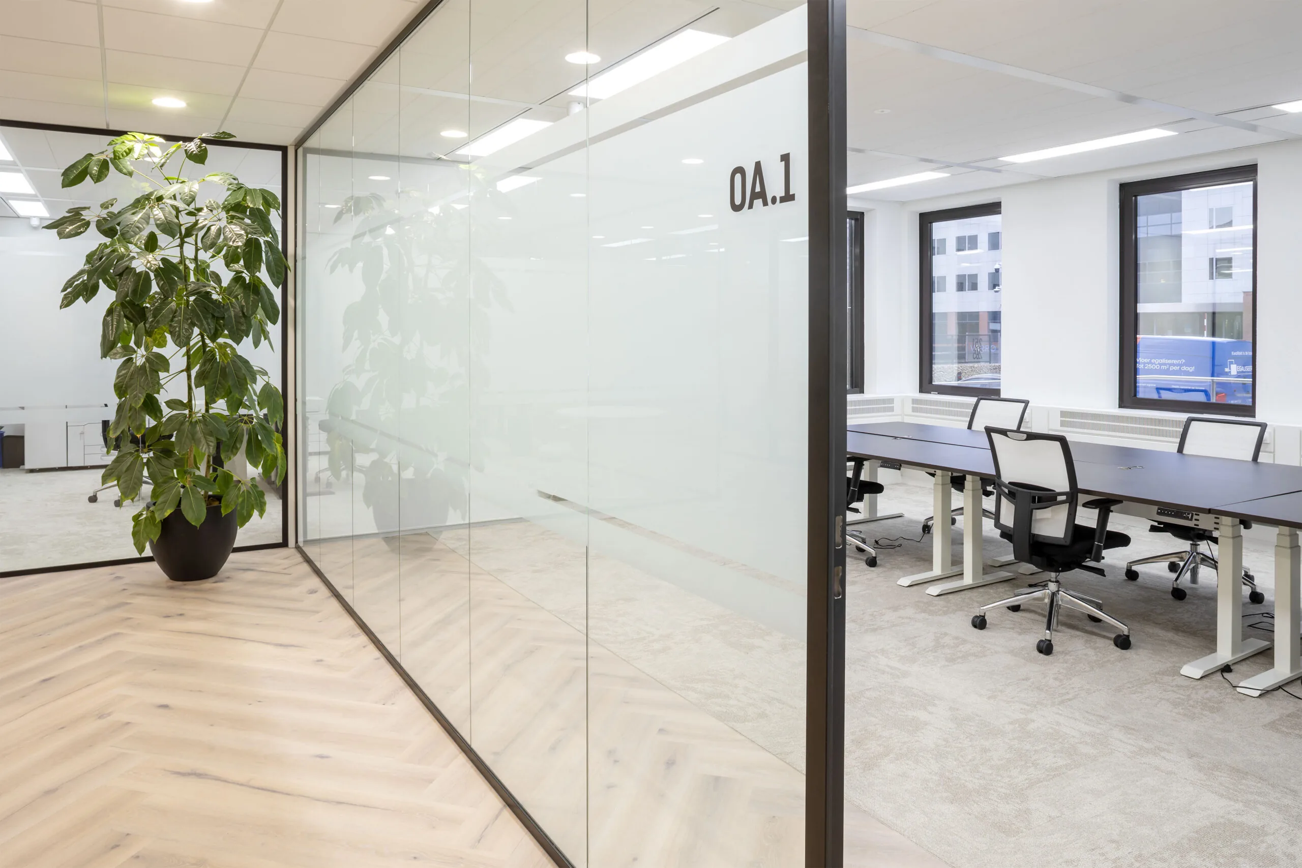 Moderne kantoorruimte aan de Kabelweg 57 in Amsterdam met glazen wanden, bureaus en bureaustoelen.