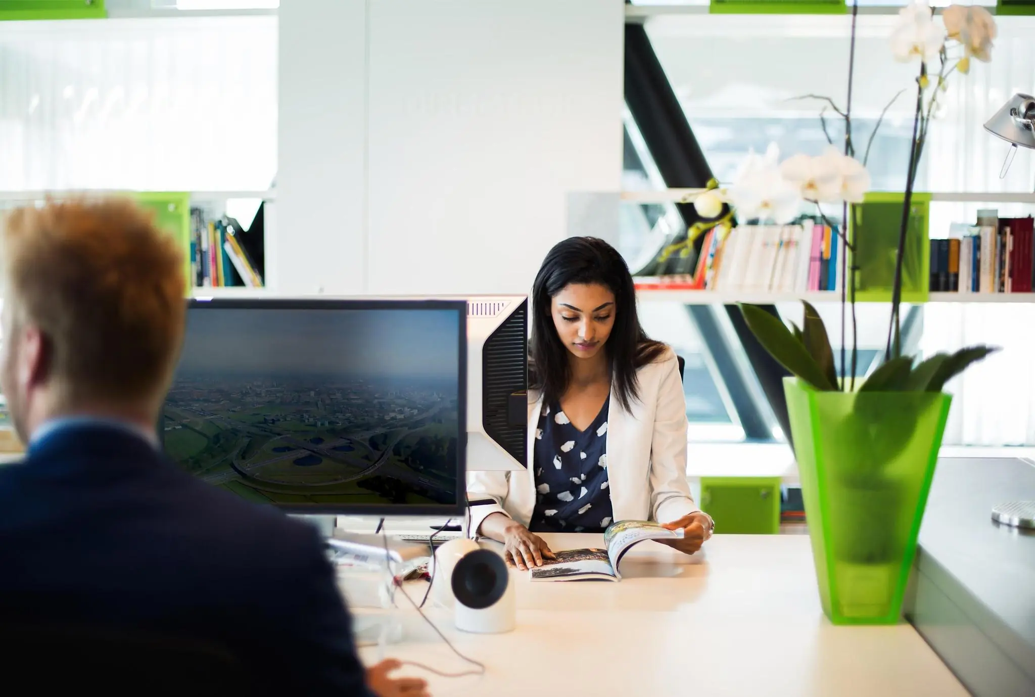 Vrouw leest een tijdschrift aan een modern bureau op een kantoor aan de Orteliuslaan.