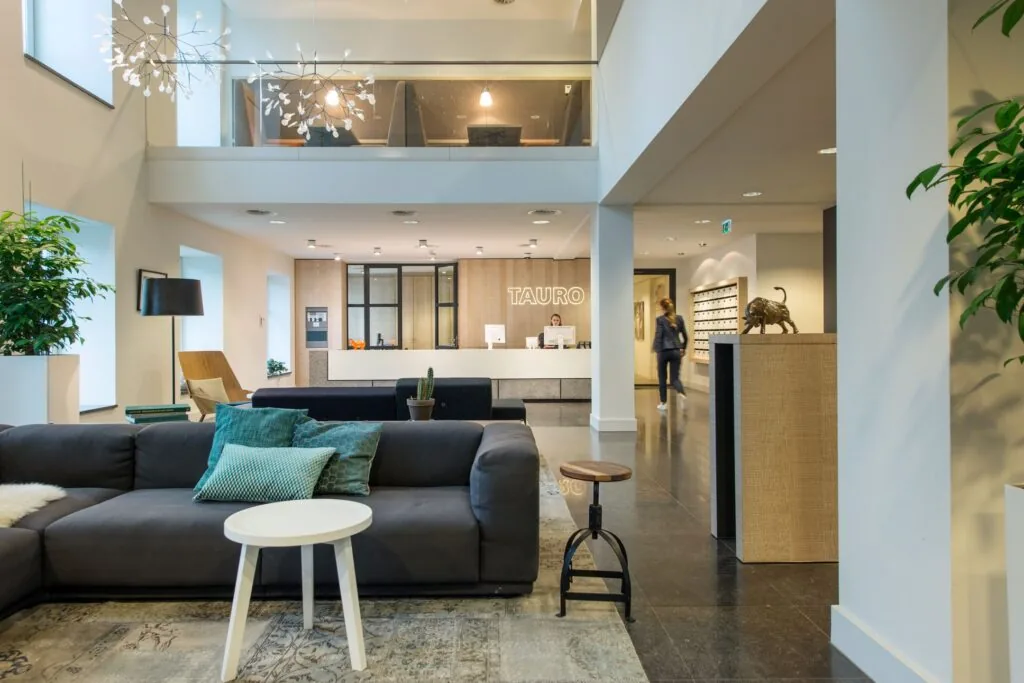Moderne en stijlvolle ontvangsthal van een kantoorruimte aan de Koninginnegracht 19 in Den Haag met loungehoek en receptiebalie van TAURO.