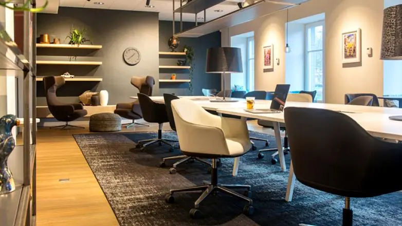 Moderne en sfeervol ingerichte kantoorruimte aan de Koninginnegracht in Den Haag met vergadertafels, bureaustoelen en loungehoek.