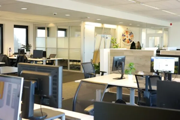 Moderne kantoorruimte aan de Radarweg met flexwerkplekken, computers en een rad van fortuin aan de muur.