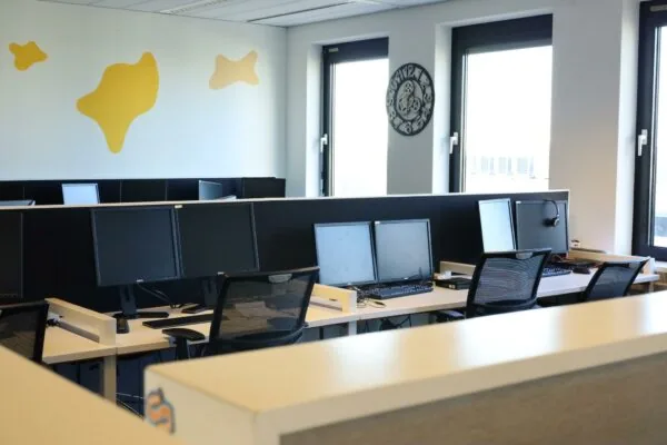 Moderne en opgeruimde kantoortuin aan de Radarweg met meerdere werkplekken, beeldschermen en bureaustoelen bij grote ramen.