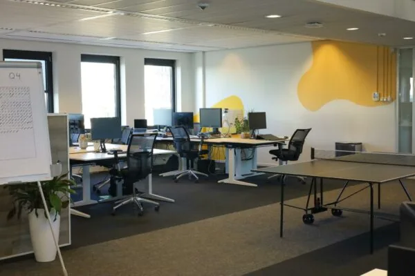 Moderne kantoorruimte aan de Radarweg met bureaus, computers, een flipover en een pingpongtafel.
