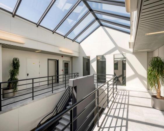 Lichte en moderne binnengang in een kantoorgebouw aan de Overschiestraat met glazen dak en trappenhuis.