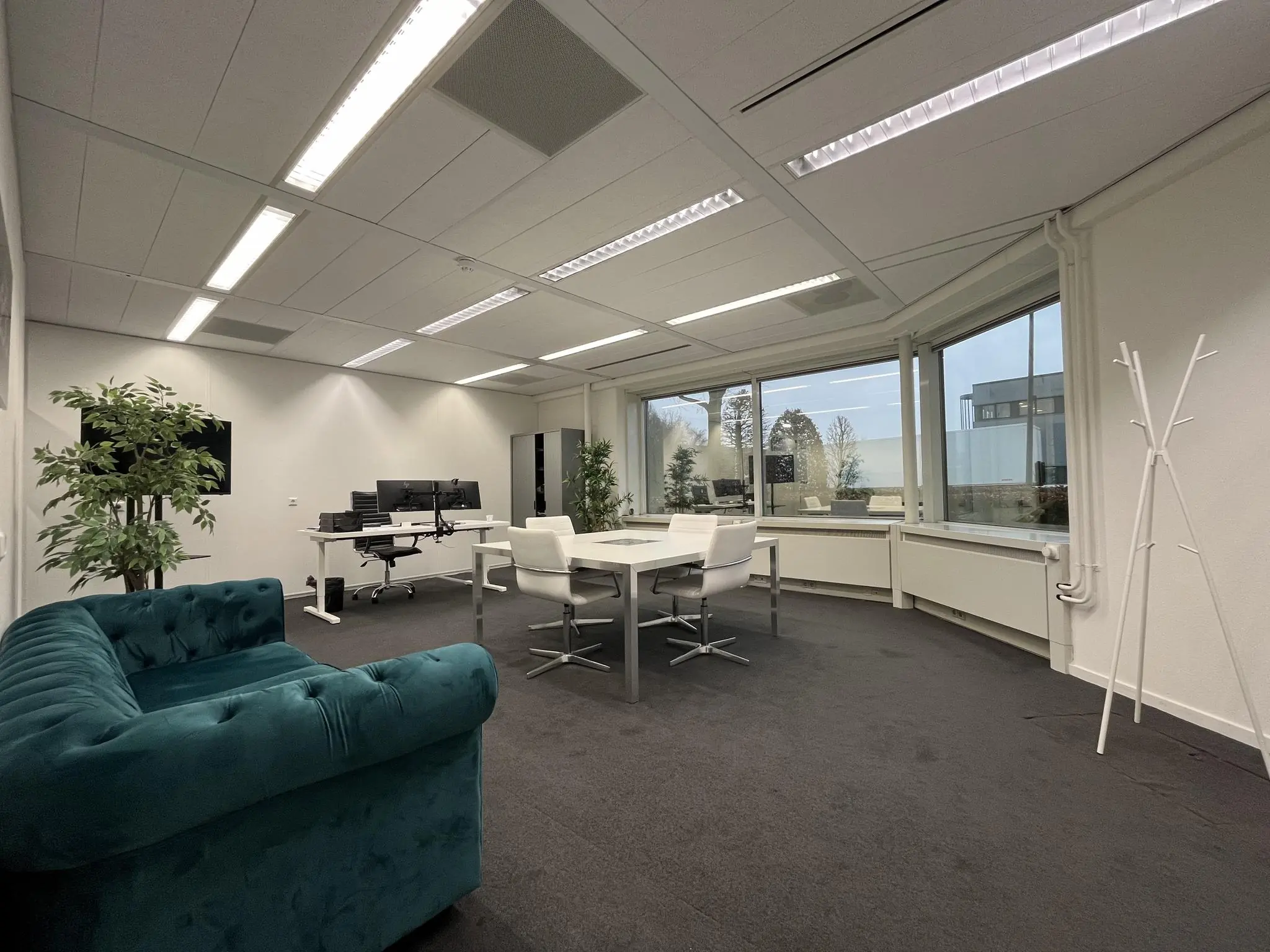 Modern kantoorinterieur aan de Savannahweg met bureaus, vergadertafel, groene bank en grote raampartijen.