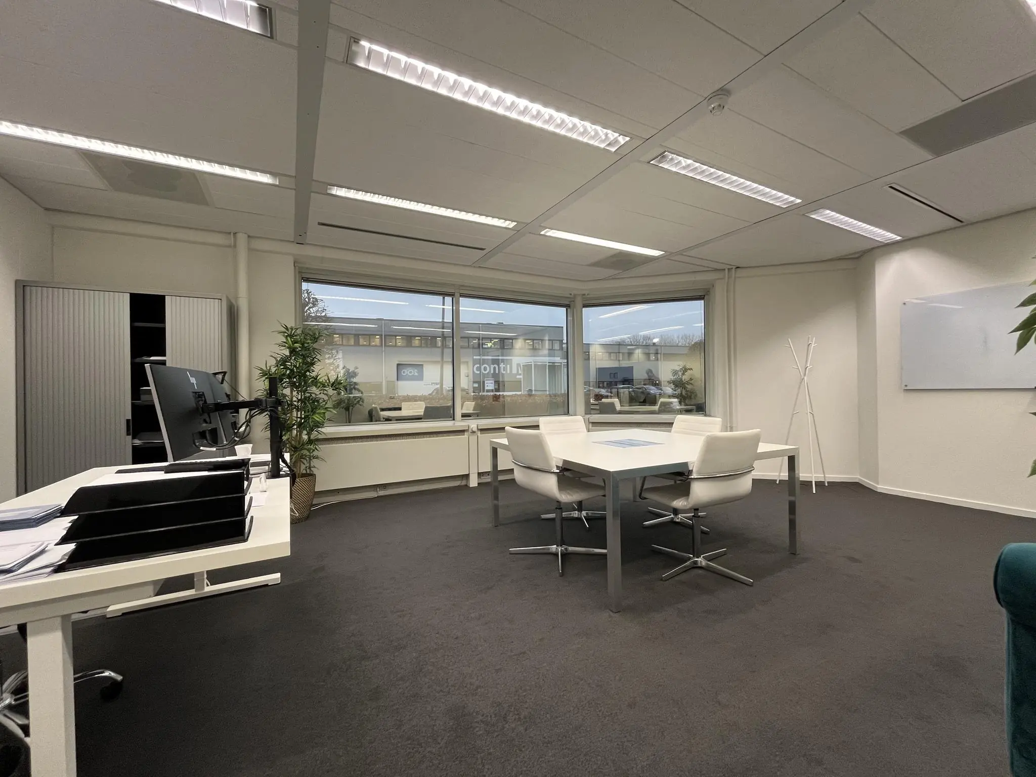 Zakelijke vergaderruimte aan de Savannahweg met een vergadertafel, bureaus, kasten en uitzicht op een bedrijvenpand.