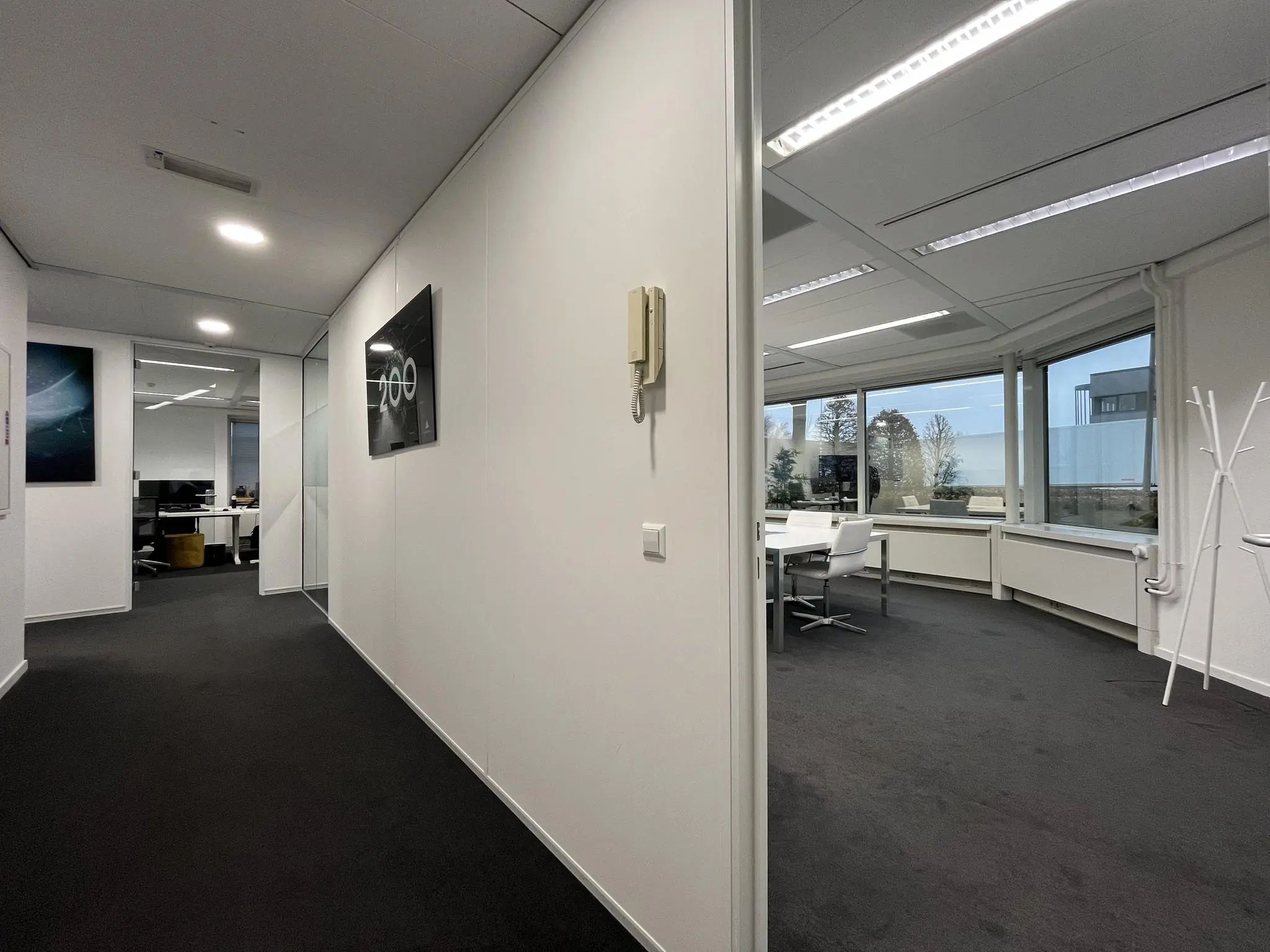 Gang en vergaderruimte in een modern kantoorpand aan de Savannahweg met witte muren, glazen wanden en uitzicht naar buiten.