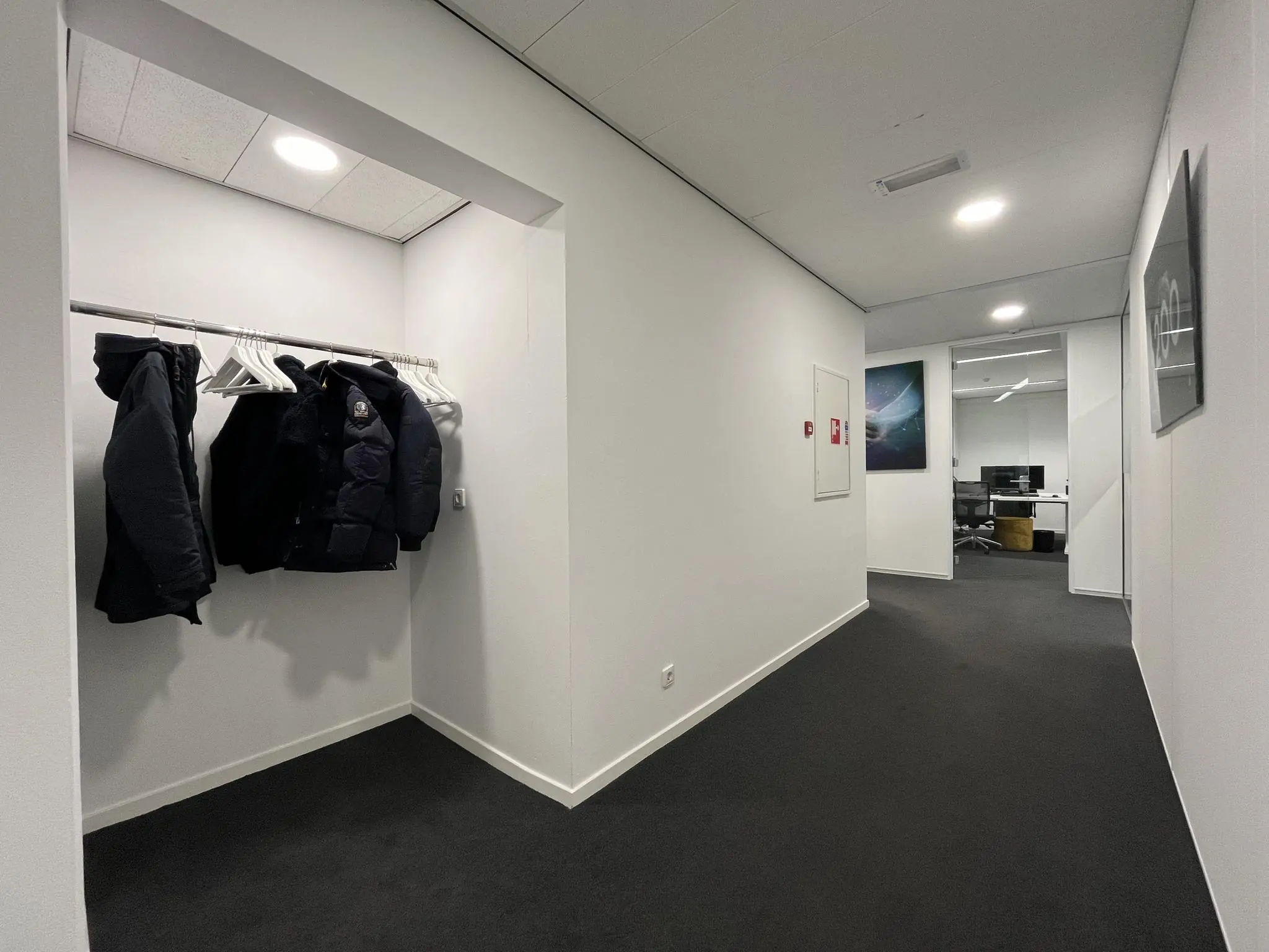Gang in een modern kantoorpand aan de Savannahweg met een open garderobe en zicht op een kantoorruimte.