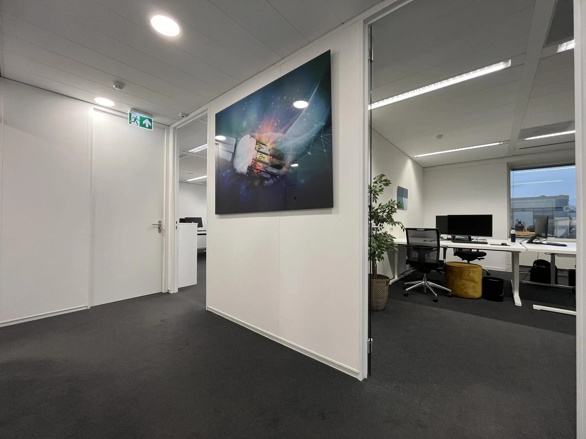 Moderne kantoorruimte aan de Savannahweg met open deuren, bureaus, computerschermen en een opvallende digitale kunstfoto aan de muur.
