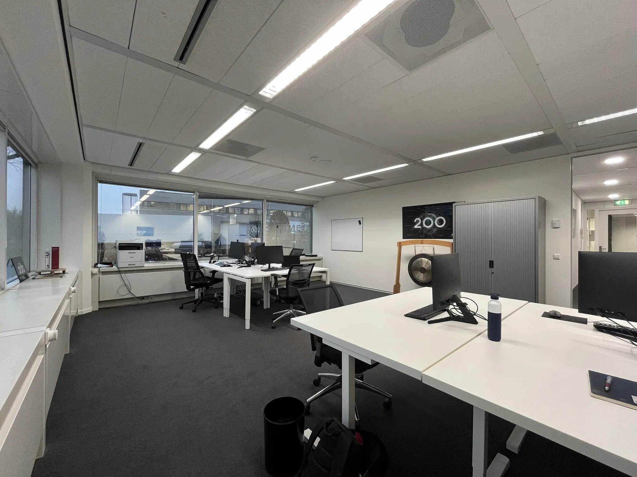 Moderne kantoorruimte aan de Savannahweg met werkplekken, computers en een grote gong voor een poster met het getal 200.