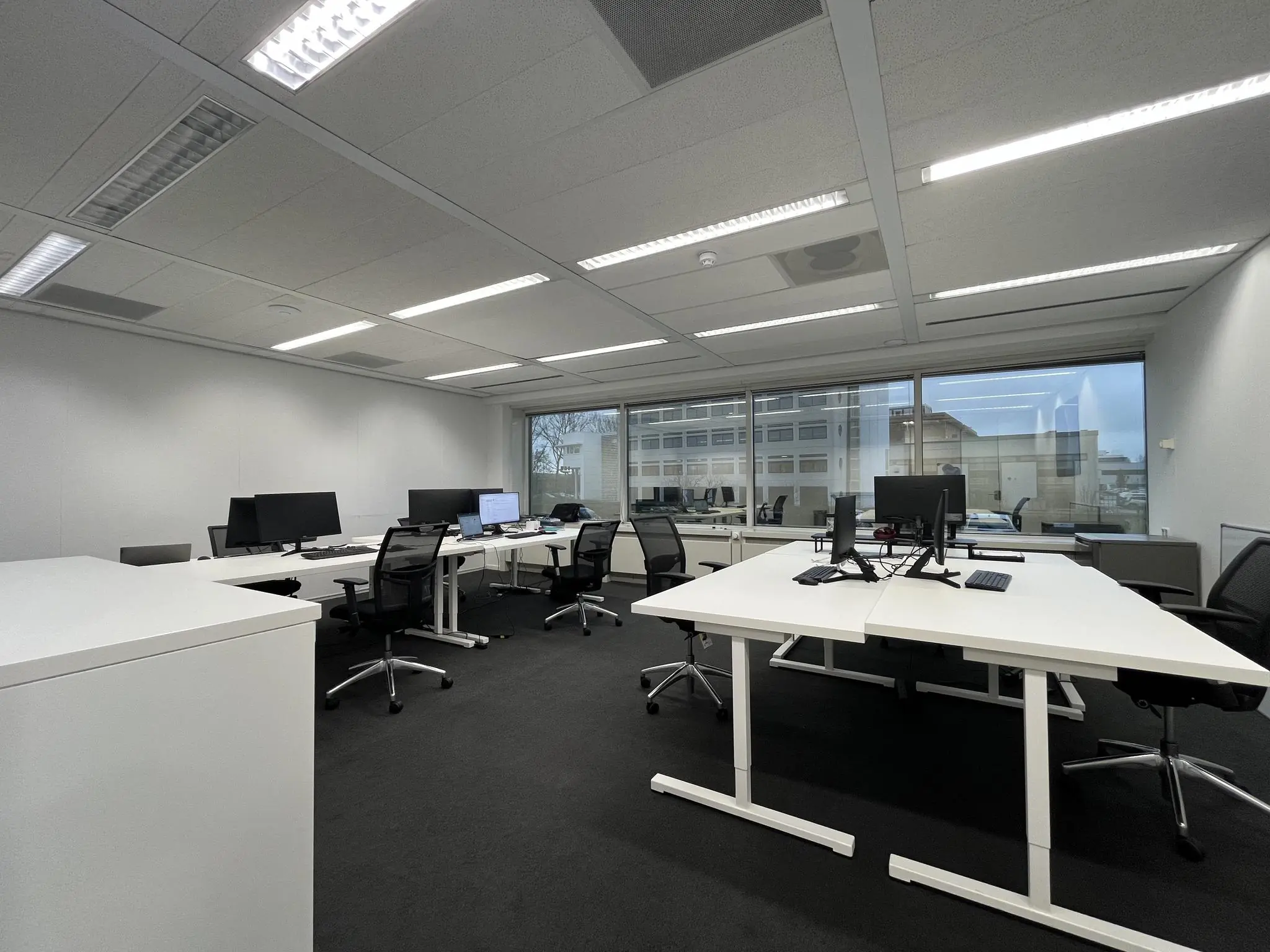 Moderne, lichte kantooruimte aan de Savannahweg met meerdere werkplekken en grote ramen met uitzicht op nabijgelegen gebouwen.