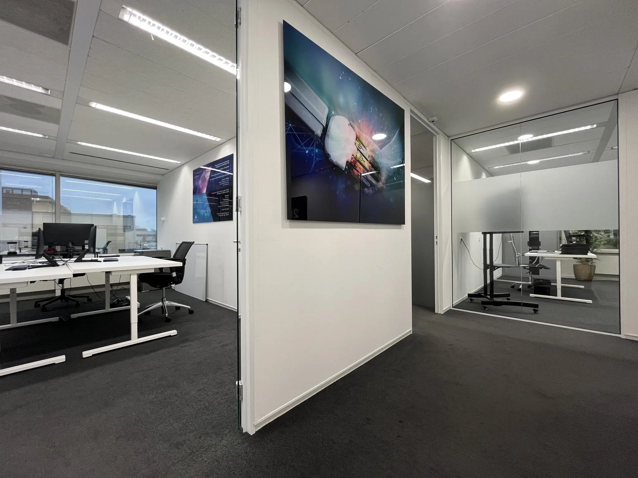Moderne kantoorruimte aan de Savannahweg met glazen wanden, werkplekken en digitale kunst aan de muur.