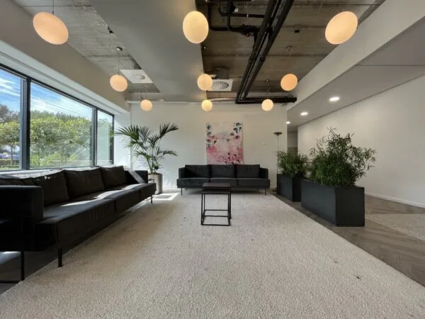 Moderne wachtruimte aan de Savannahweg met zwarte banken, planten en hangende ronde lampen.