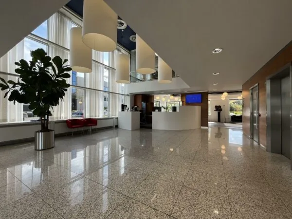 Moderne, lichte ontvangsthal van een kantoorpand aan de Savannahweg met grote ramen, hanglampen en een receptiebalie.