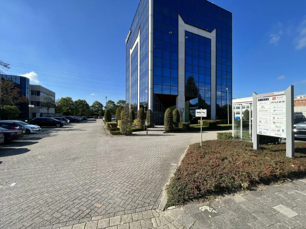 Kantoorgebouw Savannah Tower met omliggende parkeerplaatsen en bedrijvenbord aan de Savannahweg op een zonnige dag.