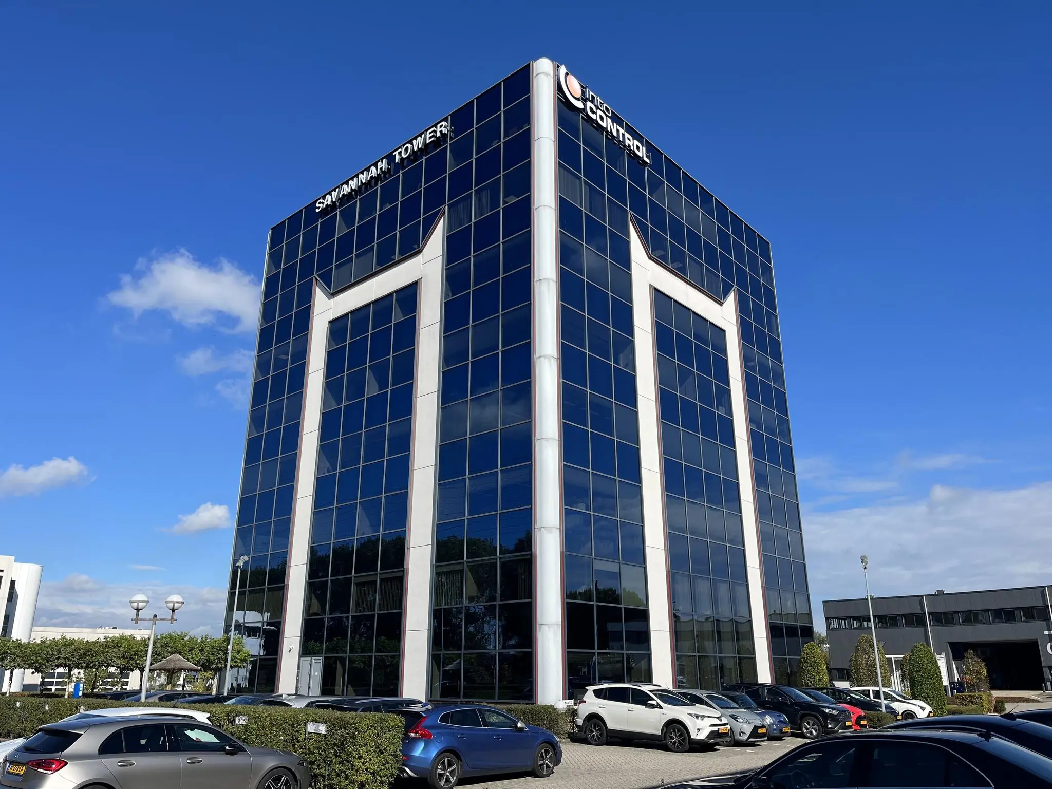 Kantoorgebouw Savannah Tower met glazen gevel en geparkeerde auto's op de voorgrond.