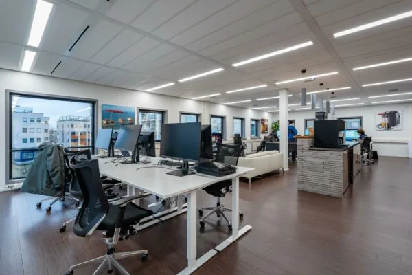 Modern kantoorinterieur aan de Barbizonlaan met bureaus, computers, medewerkers en een koffiehoek.