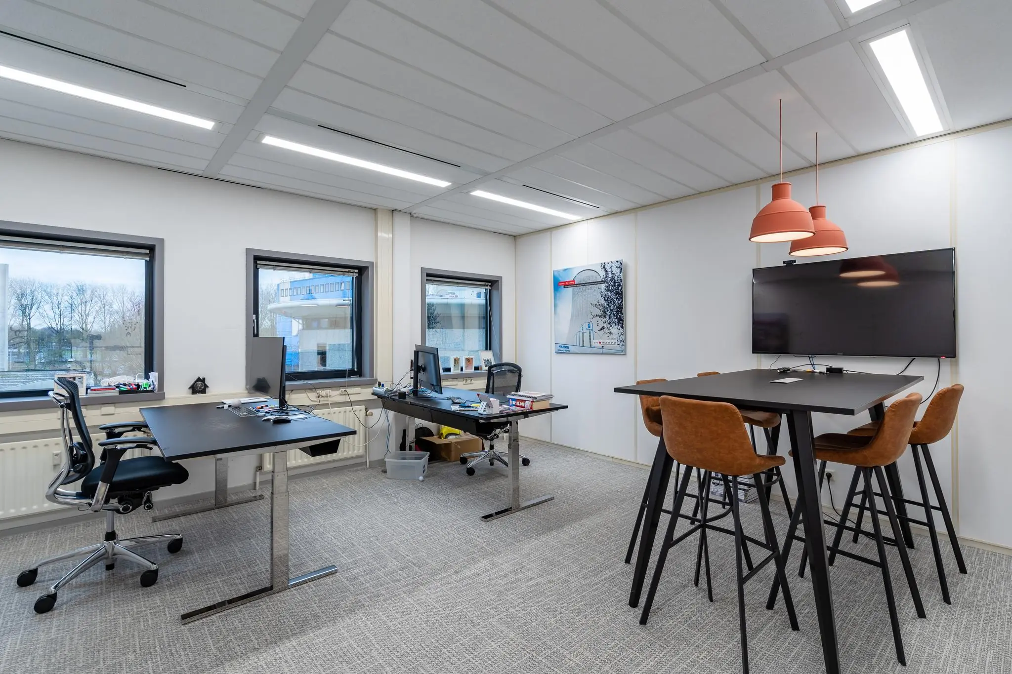 Modern kantoor op Barbizonlaan met werkplekken, vergadertafel, bureaustoelen en een flatscreen aan de muur.