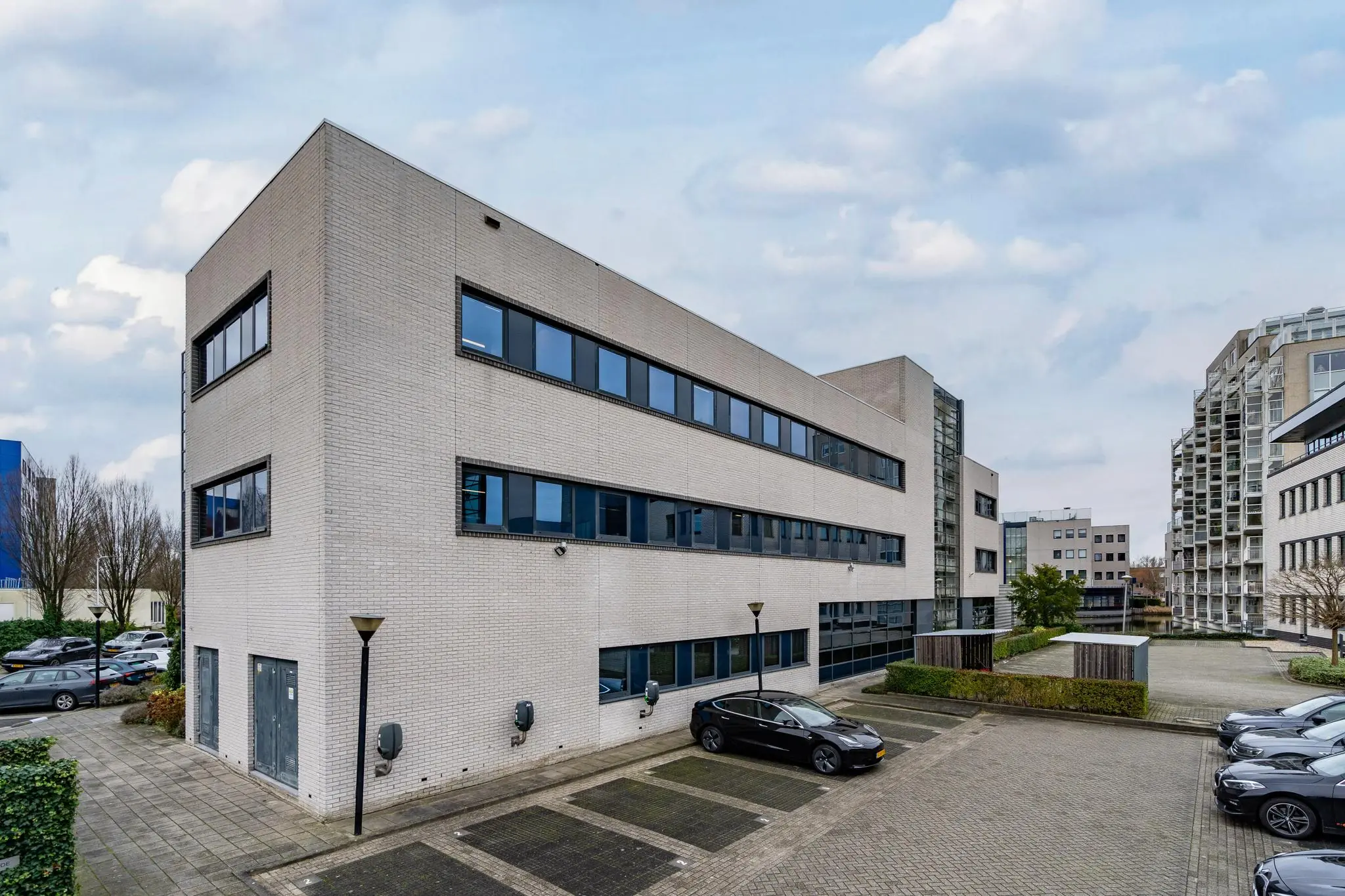 Kantoorgebouw aan de Barbizonlaan met parkeerplaatsen en omliggende moderne bebouwing.