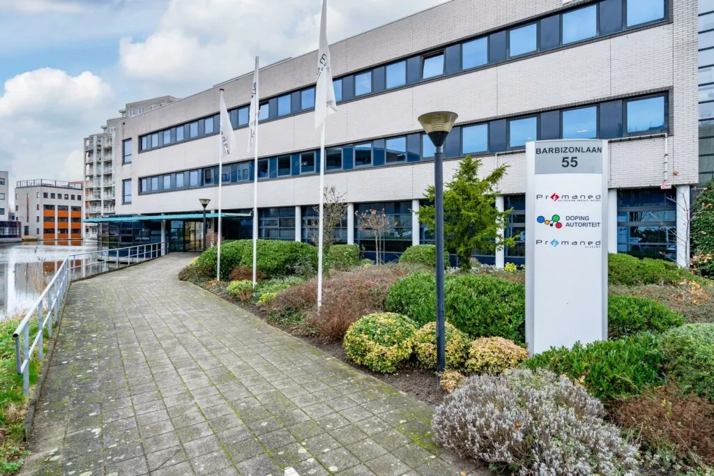 Vooraanzicht van een kantoorgebouw aan de Barbizonlaan 55 met bord van Promened en de Dopingautoriteit.