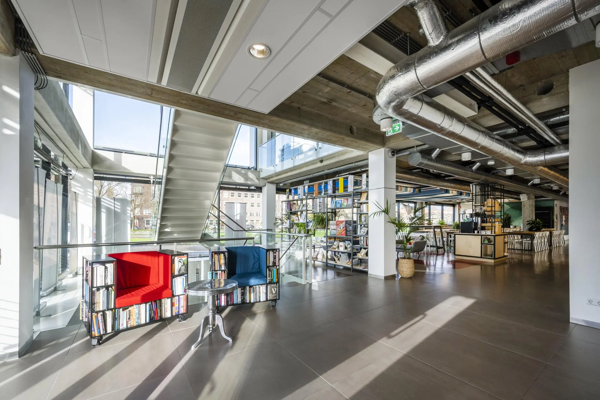 Moderne en open kantoorruimte aan de Wibautstraat met boekenkasten, kleurrijke fauteuils en industriële details.