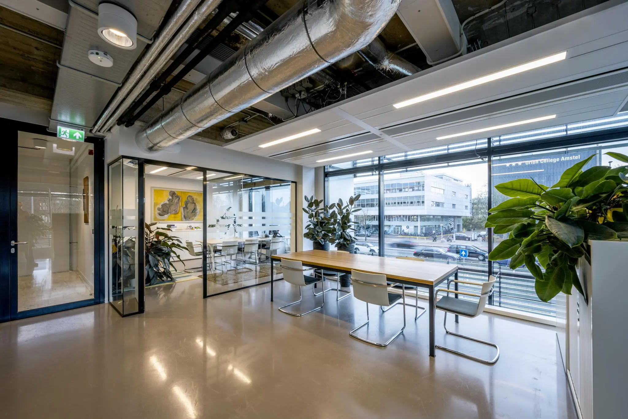 Moderne kantoorruimte aan de Wibautstraat met grote ramen, vergaderruimte en uitzicht op het Orion College Amstel.