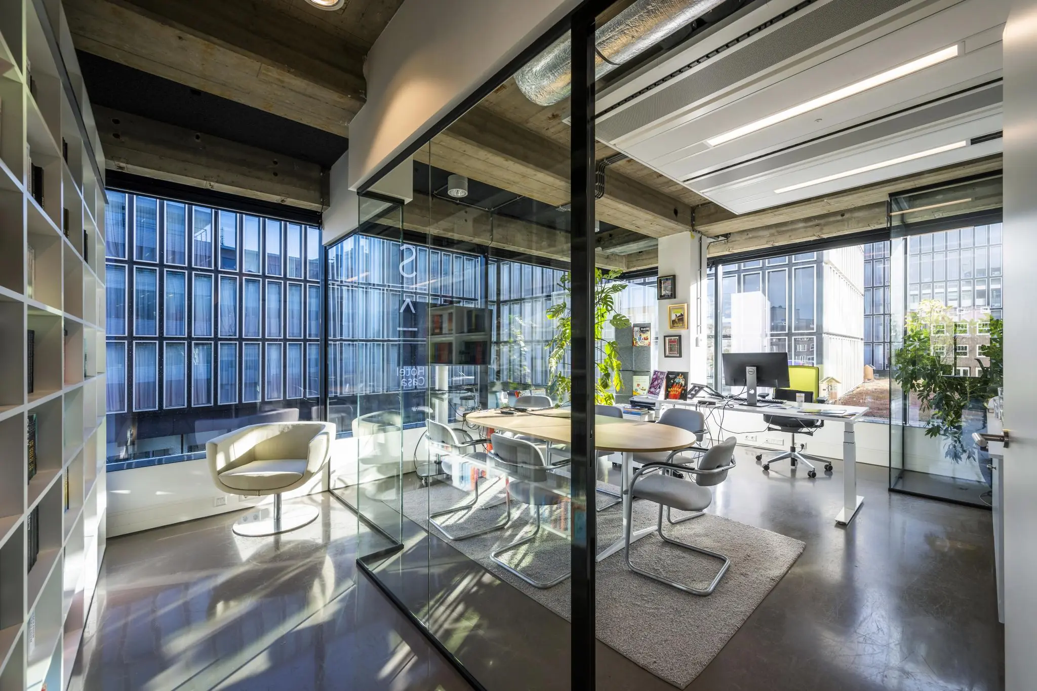 Modern kantoorinterieur aan de Wibautstraat met glazen vergaderruimte, bureaus en veel natuurlijk licht.