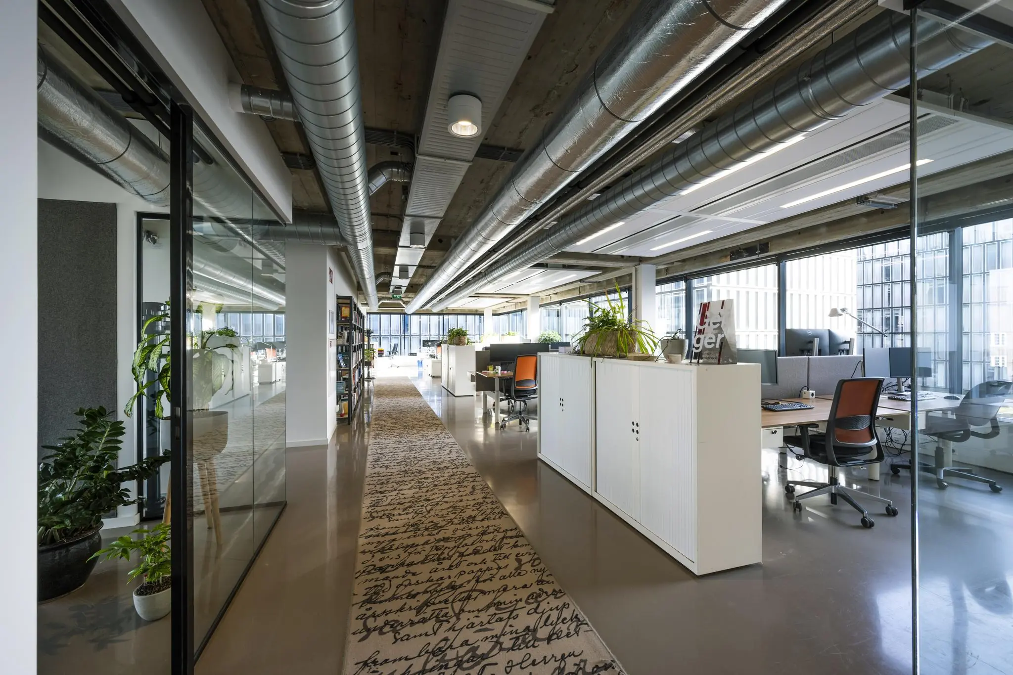 Modern ingericht kantoor aan de Wibautstraat met open werkplekken, glazen wanden en industriële plafonddetailering.