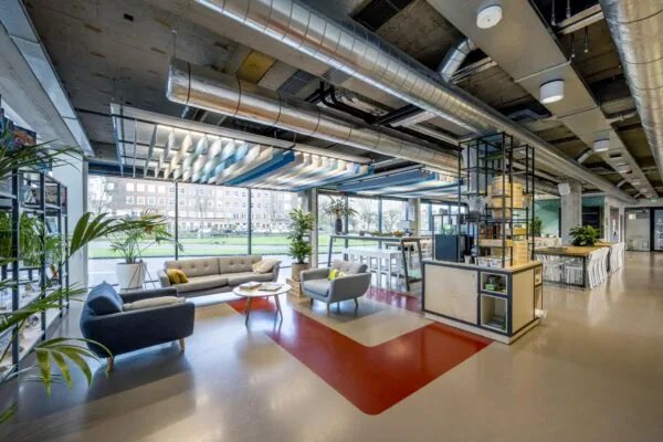 Moderne en open kantoorruimte aan de Wibautstraat met zitgedeelte, hoge plafonds en grote ramen met uitzicht op de stad.
