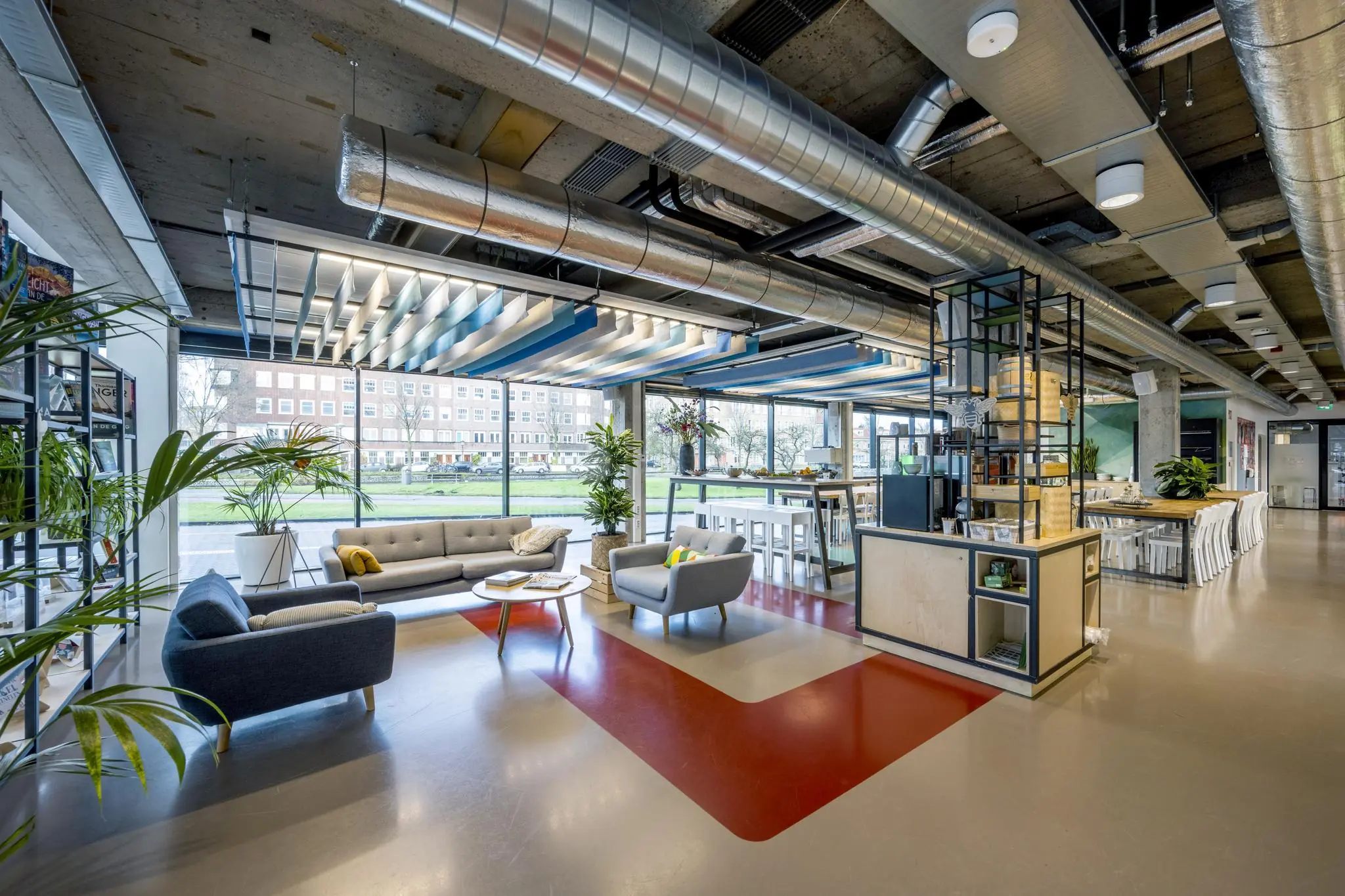 Moderne en open kantoorruimte aan de Wibautstraat met zitgedeelte, hoge plafonds en grote ramen met uitzicht op de stad.