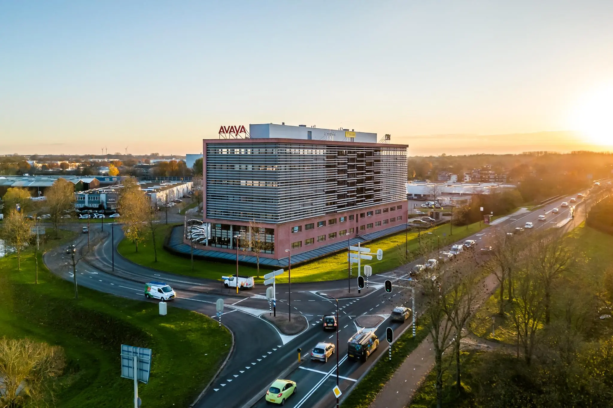 Modern kantoorgebouw aan de Marconibaan in Nieuwegein bij een druk kruispunt tijdens zonsondergang.