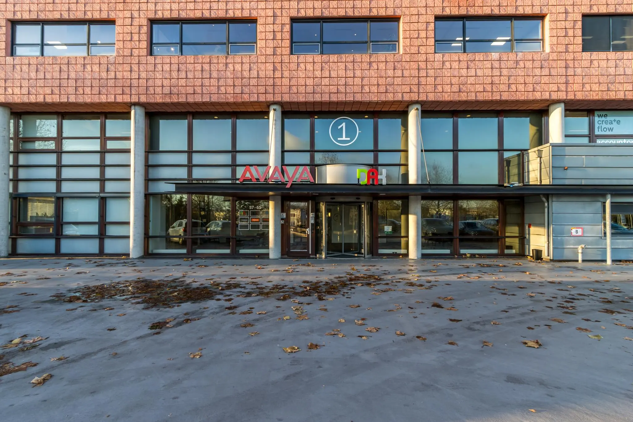 Vooraanzicht van een kantoorgebouw aan de Marconibaan met de bedrijfsnamen Avaya en DAH boven de ingang.