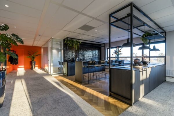 Modern kantoorinterieur aan de Marconibaan met open zithoek, keukenblok en veel natuurlijk licht.