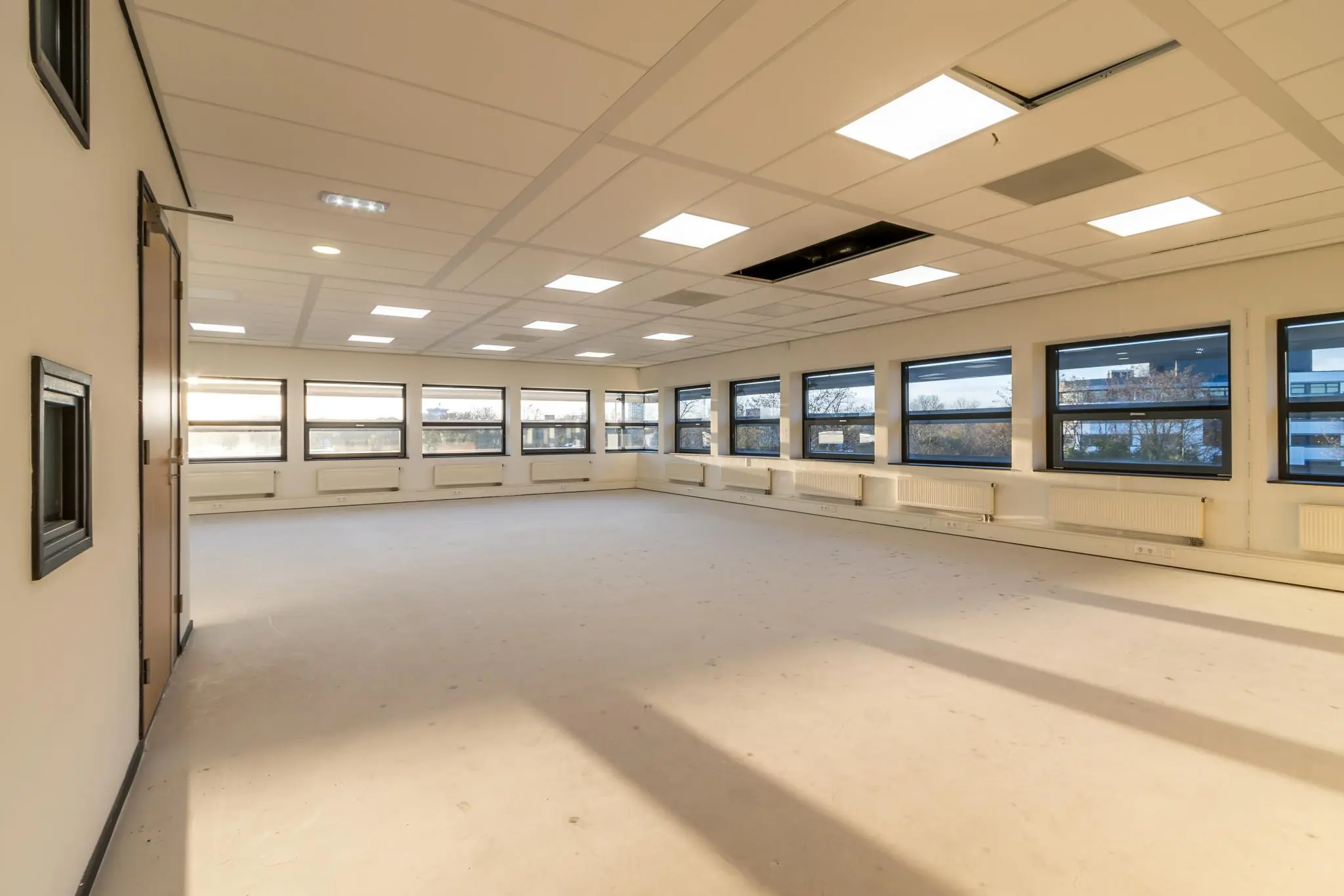 Lichte, lege kantoorruimte aan de Marconibaan met grote ramen en systeemplafond.