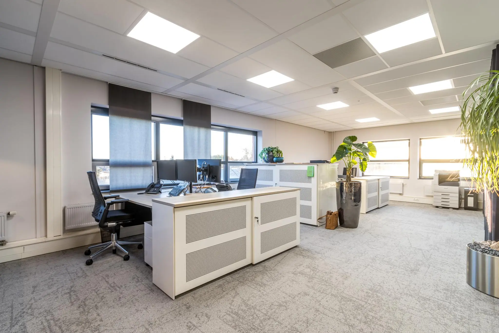 Modern en licht kantoorinterieur aan de Marconibaan met bureaus, planten en grote ramen.