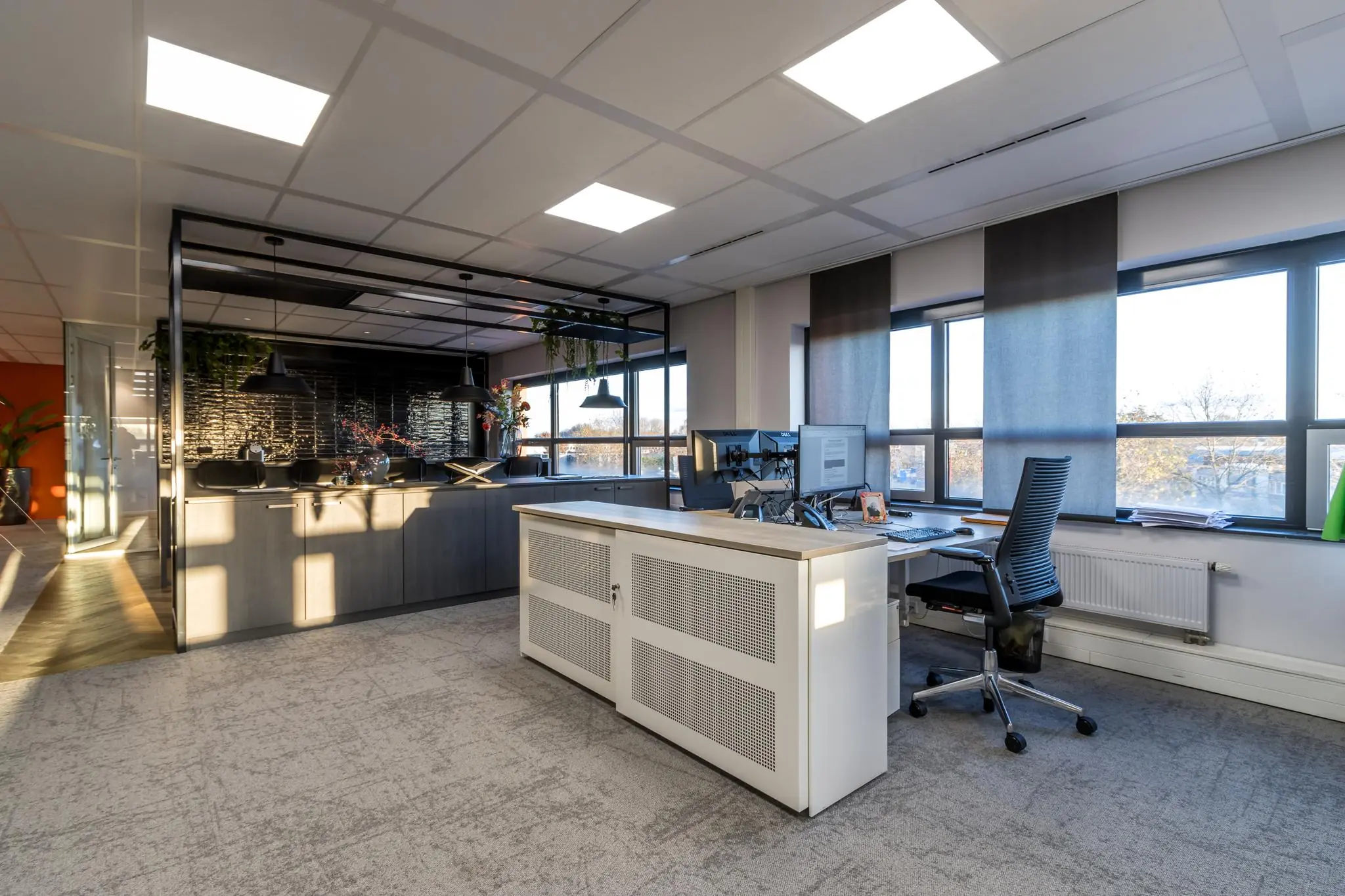Modern kantoorinterieur aan de Marconibaan met een werkplek bij het raam en een open keuken met zwarte details.