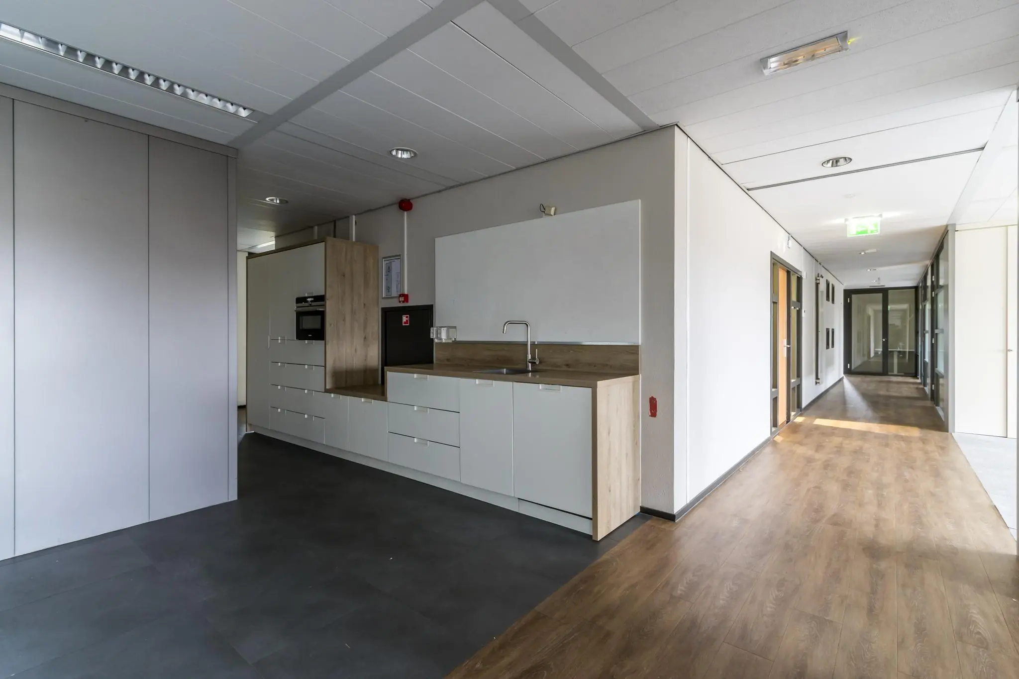 Modern kantoorinterieur met een keukenblok en een gang met houten vloer aan de Marconibaan.